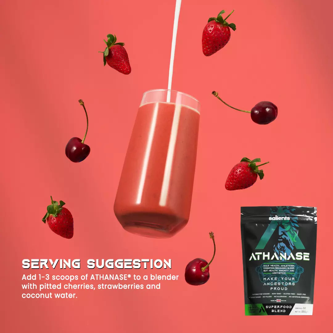 Glass of red juice with strawberries, cherries, and a package of Athanase on a pink background