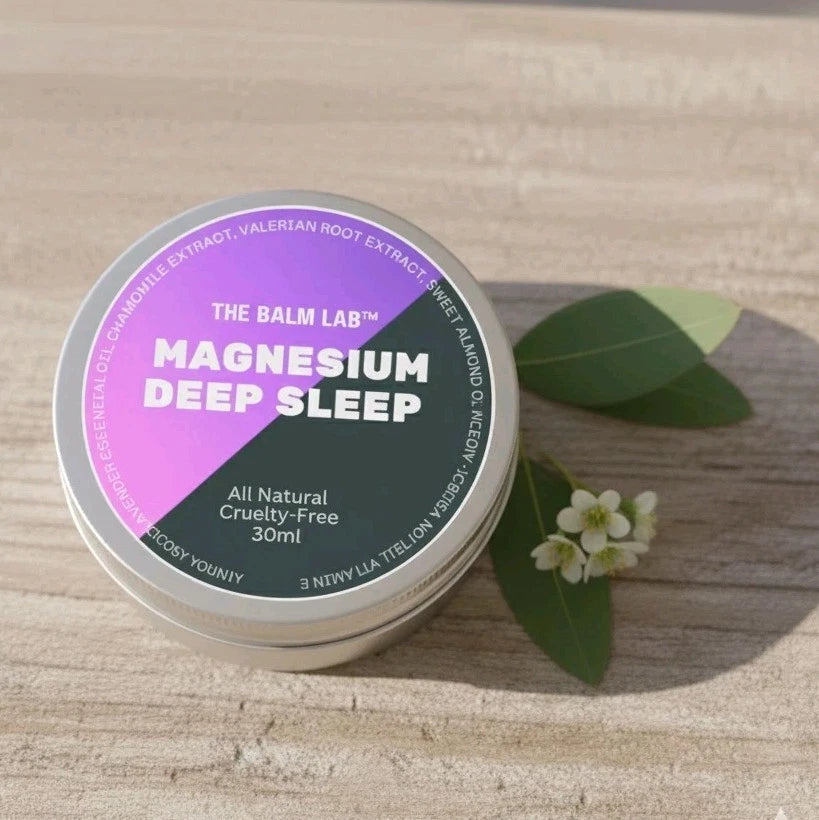Tin labeled 'The Balm Lab Magnesium Deep Sleep' on a wooden surface with leaves and flowers.